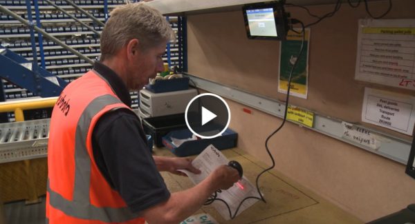 Man in orange hi-vis tabbard scanning an item in a warehouse