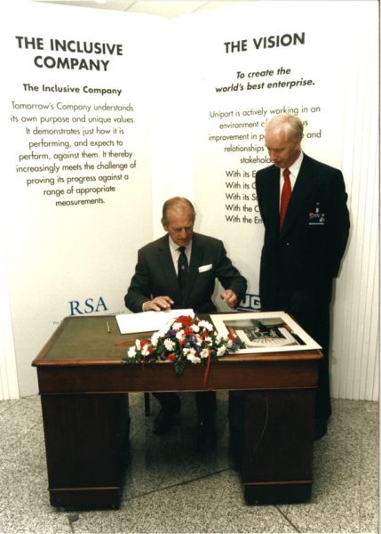 Prince Philip signs the visitors' book as John Neill looks on at Unipart in June 1995