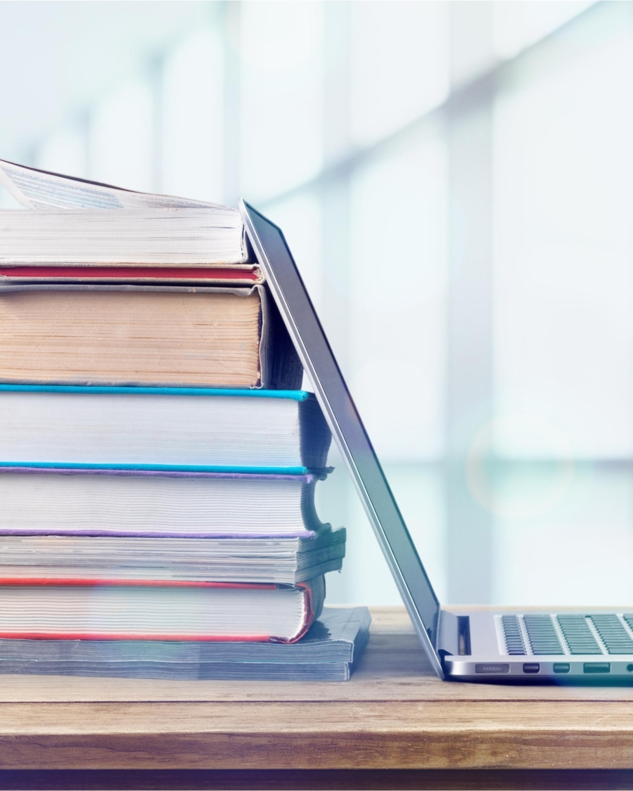 Stack of books with laptop on wooden table